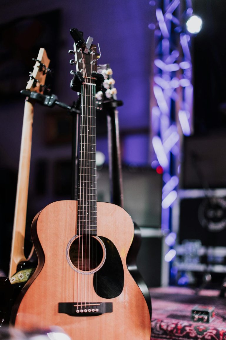 Close-up of an acoustic guitar on stage under vibrant concert lighting.