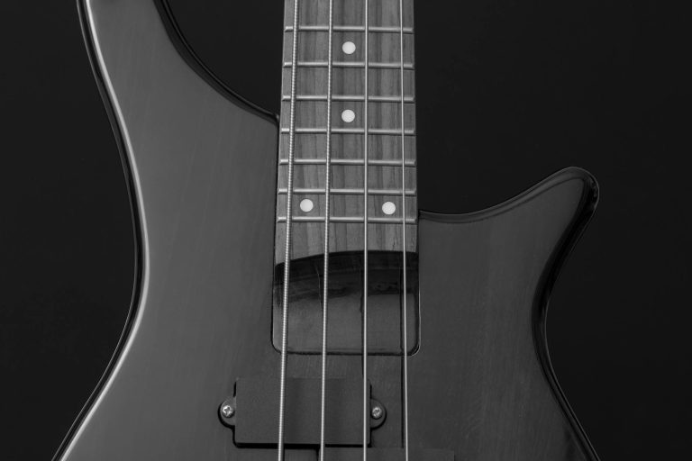 Detailed close-up of an electric guitar in black and white, showcasing strings and body.