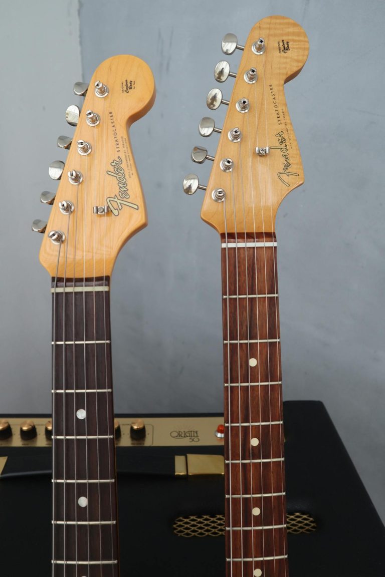 Detailed shot of two wooden electric guitar headstocks with tuning pegs.